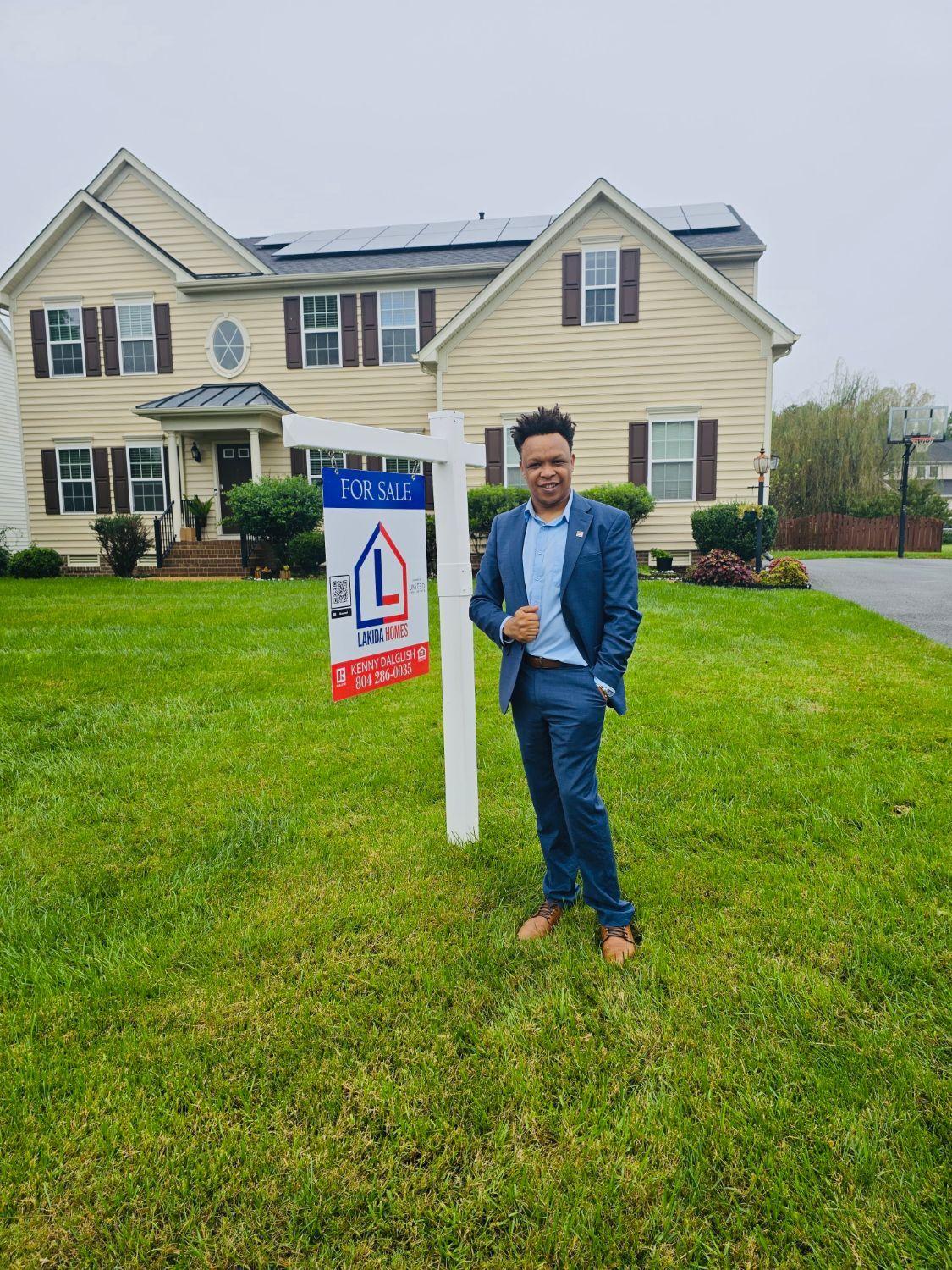 Kenny Dalglish beside a Lakida Homes For Sale sign in front of a two-story home